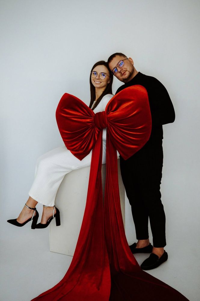Para w eleganckiej sesji studyjnej z dużą czerwoną kokardą